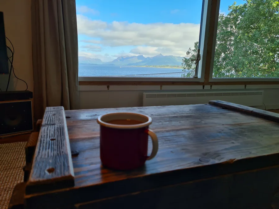 Fotografi av kaffekopp på trebord foran vindu med utsikt