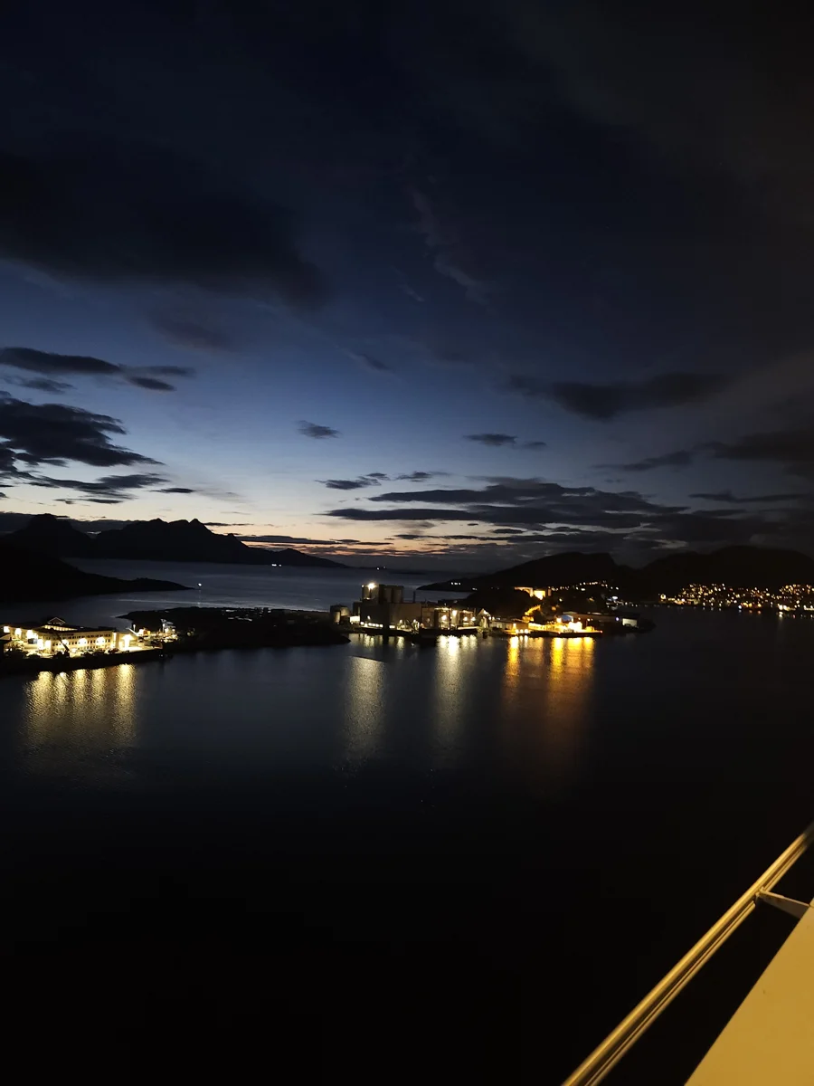 Ekte nattbilde av en opplyst havn og fjord i skumringen, tatt håndholdt med mobiltelefon